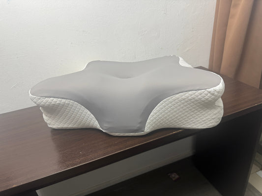 An ergonomic JCHealth adjustable contour pillow with customizable layers, showing the side-sleeper neck support design on a dark wooden display table