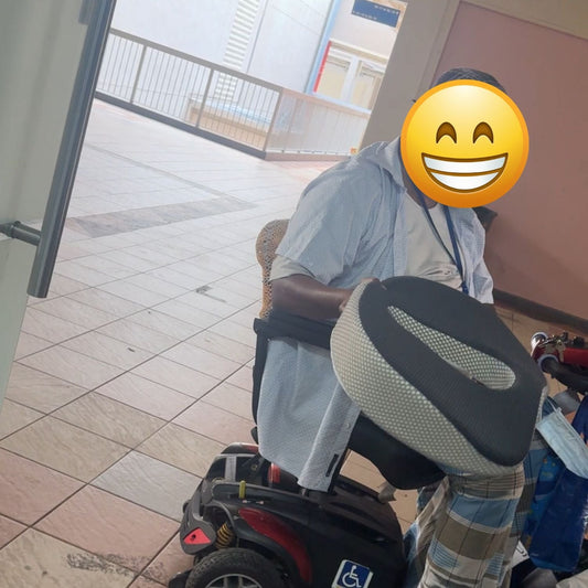 Elderly Singapore senior holding JC Health anatomical donut cushion for back pain relief outside Waterloo Street showroom.