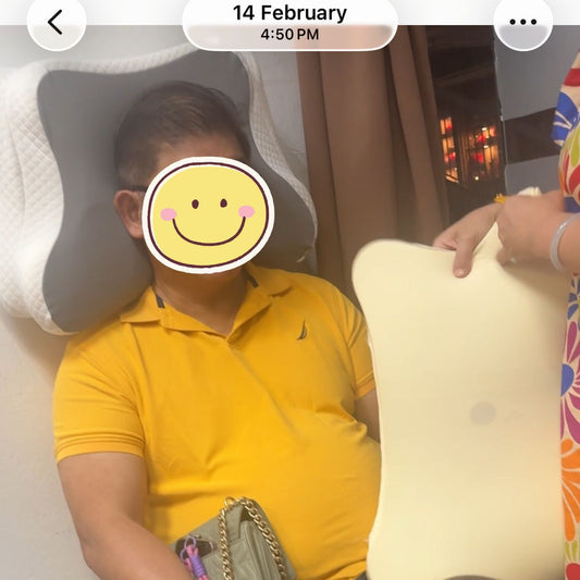 JC Health founder demonstrating the 30-second vertical Wall Test at Waterloo Centre showroom, adjusting layers of the grey butterfly-shaped adjustable pillow to find the perfect neck alignment for a customer