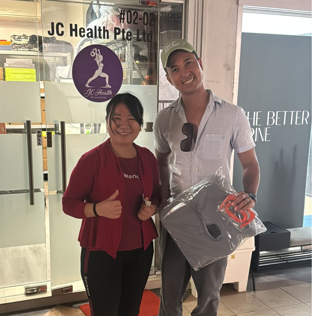 JC Health Singapore owner and a Canadian tourist holding a blue donut seat cushion for long-haul flight comfort in front of the JC Health storefront